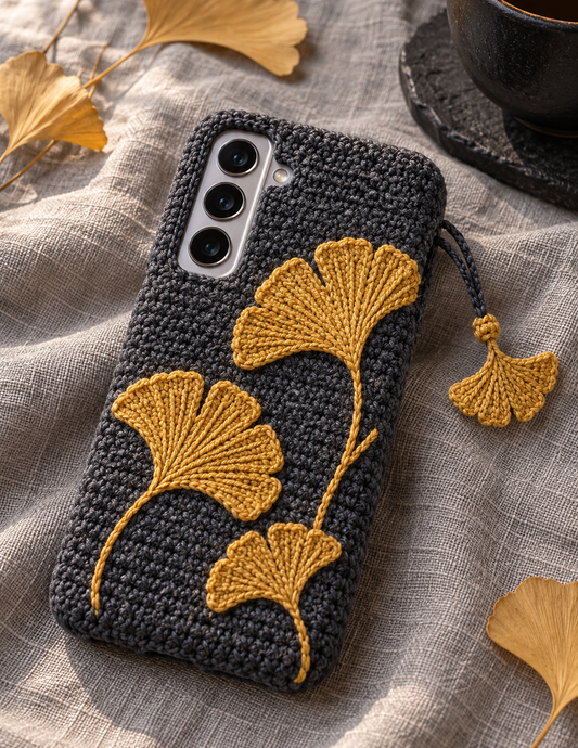 KI-Konzept einer gehäkelten Handyhülle mit dem Motiv Goldene Ginkgoblätter für Samsung Galaxy S25